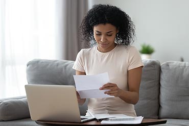 woman looking happy to receive mail in front of her laptop